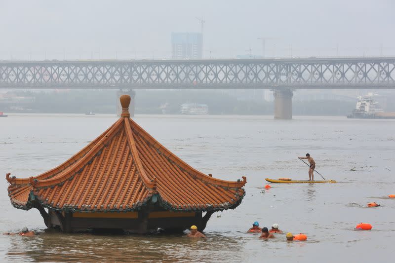 People swim near a pavilion partially submerged in floodwaters following heavy rainfall in Wuhan