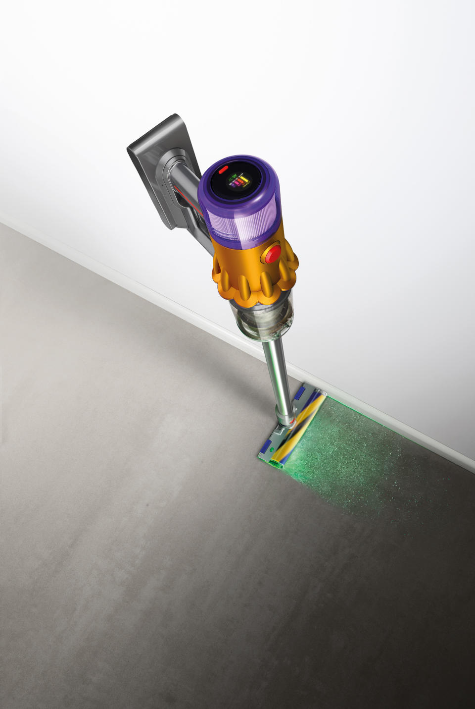 Overhead shot of a purple, silver and gold Dyson V12™ Detect Slim Absolute Extra cordless vacuum cleaner lighting up in green dust particles.