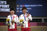 Shanju Bao, left, and Tianshi Zhong of Team China hug celebrate their gold medals during a medal ceremony for the track cycling women's team sprint finals at the 2020 Summer Olympics, Monday, Aug. 2, 2021, in Izu, Japan. (AP Photo/Christophe Ena)