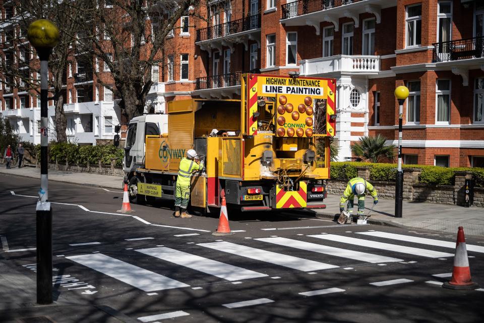 LONDON, ENGLAND - MARCH 24: A Highways Maintenance team takes advantage of the COVID-19 coronavirus lockdown and quiet streets to re-paint the iconic Abbey Road crossing on March 24, 2020 in London, England. The Beatles made the pedestrian crossing famous after featuring a photograph of the group walking on it, near to Abbey Road Studios. The album and connected artwork celebrated its fiftieth anniversary last year. British Prime Minister, Boris Johnson, announced strict lockdown measures urging people to stay at home and only leave the house for basic food shopping, exercise once a day and essential travel to and from work. The Coronavirus (COVID-19) pandemic has spread to at least 182 countries, claiming over 10,000 lives and infecting hundreds of thousands more. (Photo by Leon Neal/Getty Images)