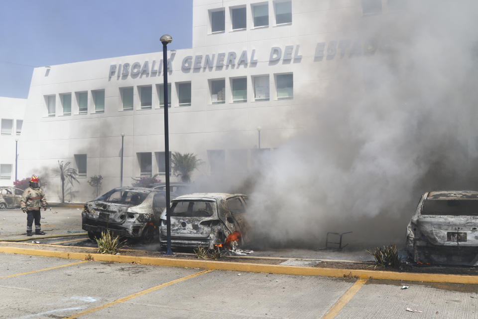 A firefighter watches cars burn at the state's Attorney General's Office after students from a rural teachers' college set them on fire to protest the shooting of one of their colleagues during a confrontation with police the previous week in Chilpancingo, Mexico, Tuesday, March 12, 2024. (AP Photo/Alejandrino Gonzalez)