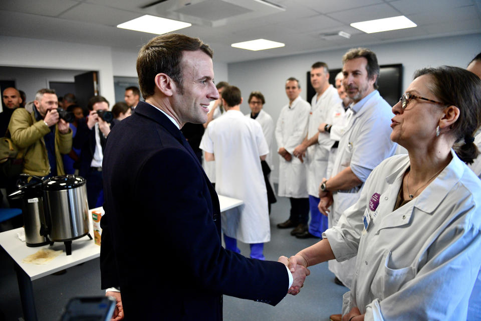 French President Emmanuel Macron shakes hands with medical staff as he visits the Pitie-Salpetriere hospital in Paris Thursday Feb. 27, 2020. As virus fears mount in France because of the outbreak in neighboring Italy, French President Emmanuel Macron is visiting a Paris hospital that has been in the forefront of testing and treating patients with the virus and where the latest virus patient died in France.( Martin Bureau, Pool via AP)