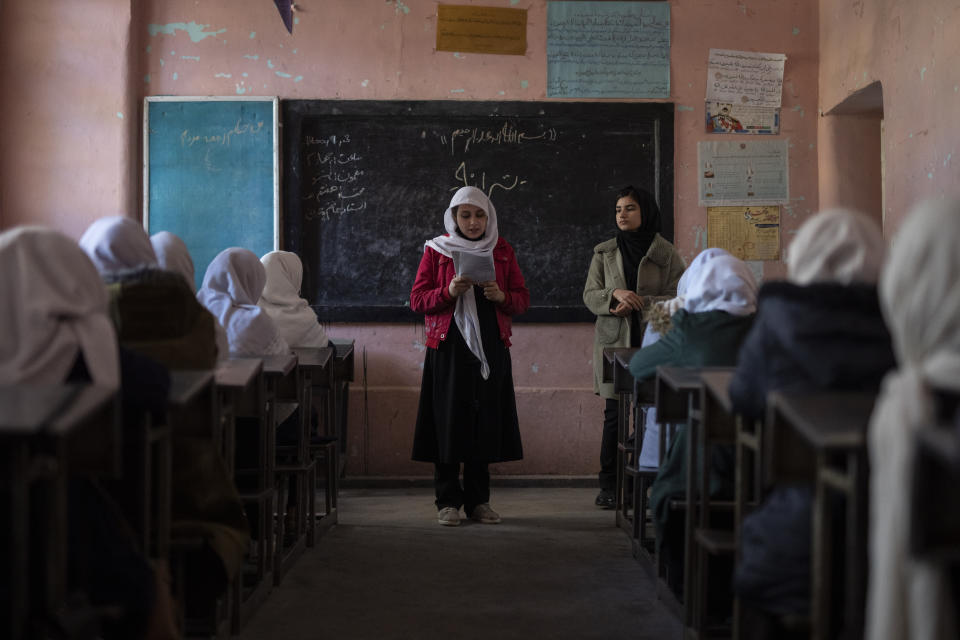 An Afghan girl reads in a classroom next to her teacher at Tajrobawai Girls High School, in Herat, Afghanistan, Thursday, Nov. 25, 2021. While most high school girls in Afghanistan are forbidden to attend class by the country's Taliban rulers, one major exception are those in the western province of Herat. For weeks, girls there have been attending high school classes, thanks to a unique effort by teachers and parents to persuade local Taliban administrators to allow schools to reopen. (AP Photo/Petros Giannakouris)