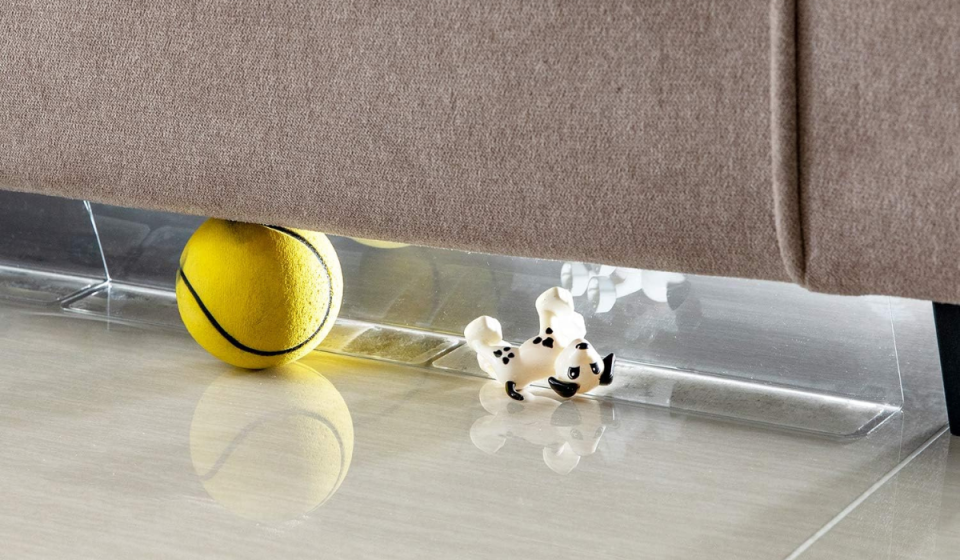 the clear toy blockers placed under a sofa, keeping toys from going underneath