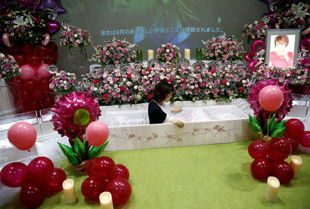 A staff sits in a casket next an altar decorated with flowers and balloons as she demonstrates Okuribito funeral's funeral service at the Life Ending Industry Expo in Tokyo, Japan, August 22, 2016. REUTERS/Kim Kyung-Hoon