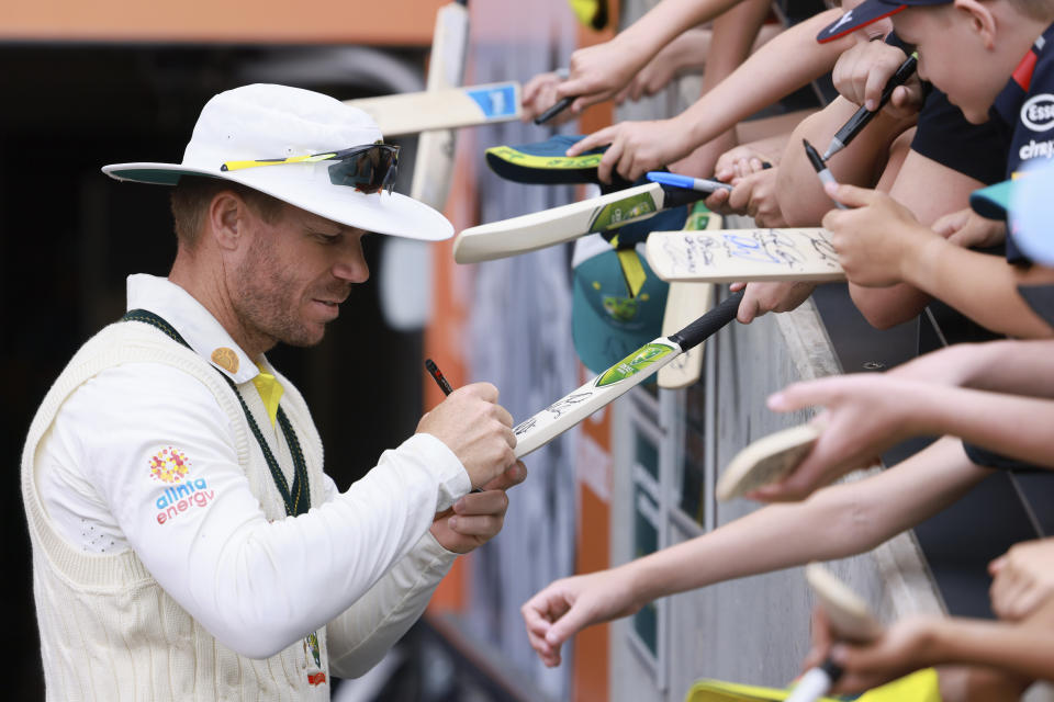 Australia's David Warner, left, signs autographs for young cricket fans after Australia's win over the West Indies on the fourth day of their cricket test match in Adelaide, Sunday, Nov. 11, 2022. (AP Photo/James Elsby)