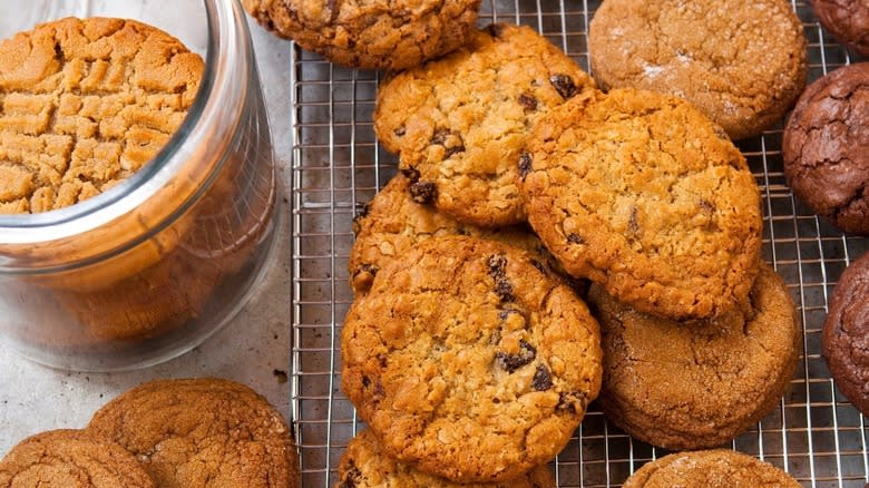 Baking sheet with a variety of cookies, as well as a glass jar full of cookies.