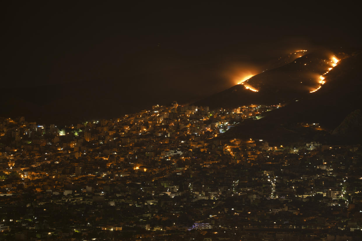 The fire burns on a hill near Korydallos, west of Athens, early Wednesday, June 29, 2022. Dozens of firefighters, are battling a brush fire west of Athens. No injuries have been reported. (AP Photo/Petros Giannakouris)