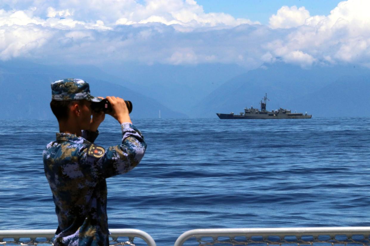 In this photo provided by China’s Xinhua News Agency, a People's Liberation Army member looks through binoculars during military exercises as Taiwan’s frigate Lan Yang is seen at the rear, on Friday, Aug. 5, 2022. China is holding drills in waters around Taiwan in response to a recent visit by U.S. House Speaker Nancy Pelosi. (Lin Jian/Xinhua via AP)