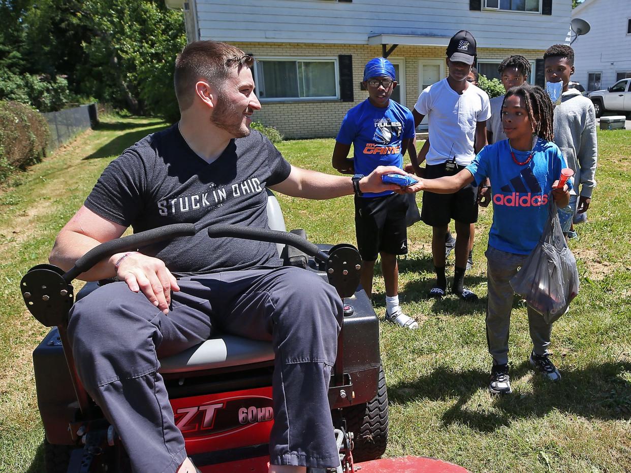 AJ Mack, 10, shares an ice cream bar with Matt Parisi as he prepares to mow the lawn June 17 in Kent.