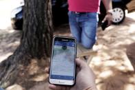 FILE PHOTO: Uber driver holds his cell phone showing the queue to pick up passengers departing Guarulhos International Airport in Sao Paulo