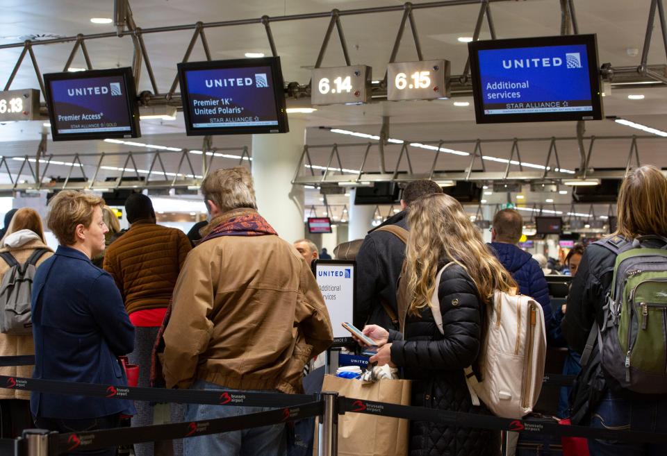 People wait to check in to a flight to Chicago at the United Airlines counter in the main terminal of Brussels International Airport in Brussels,, March 12, 2020. The European Union has slammed the new anti-virus travel ban announced by U.S. President Donald Trump on Wednesday.