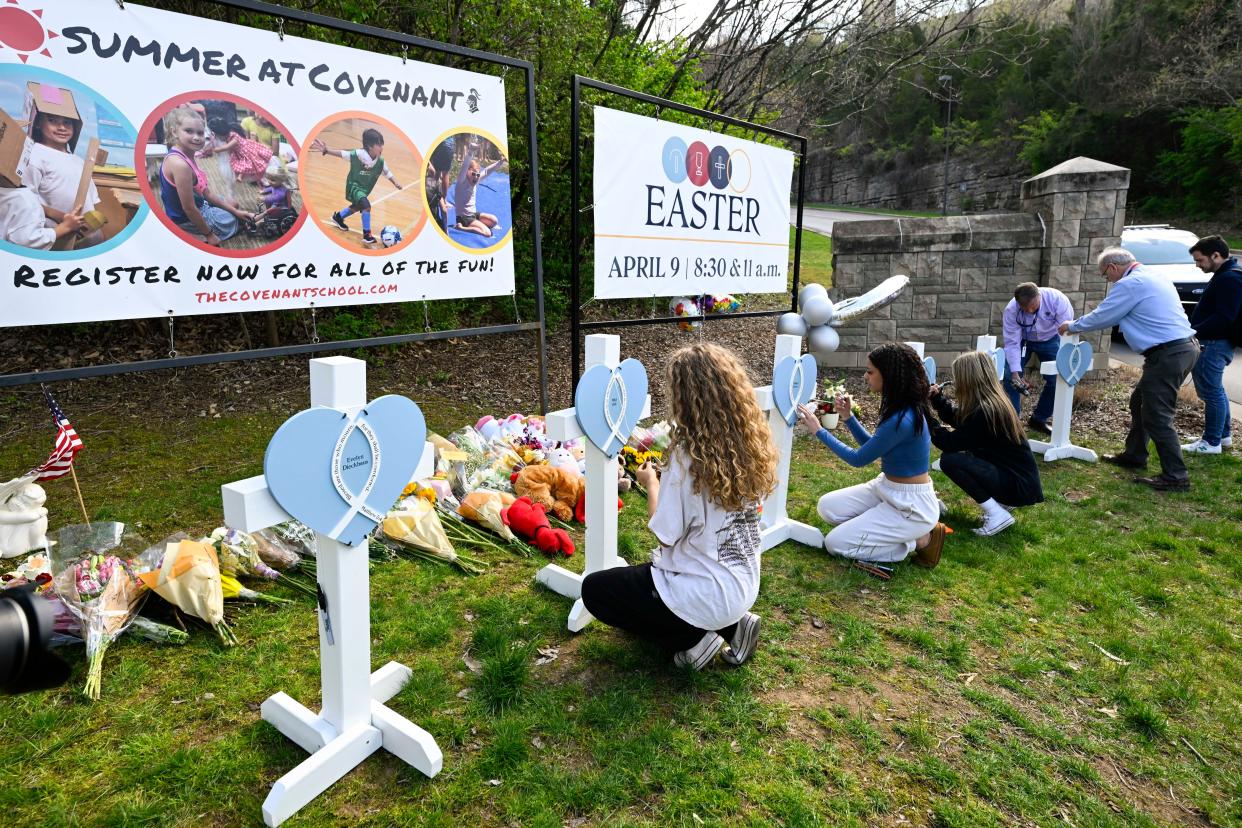 Mourners write messages on memorial crosses at an entry to The Covenant School in Nashville, Tenn., on March 28, 2023.