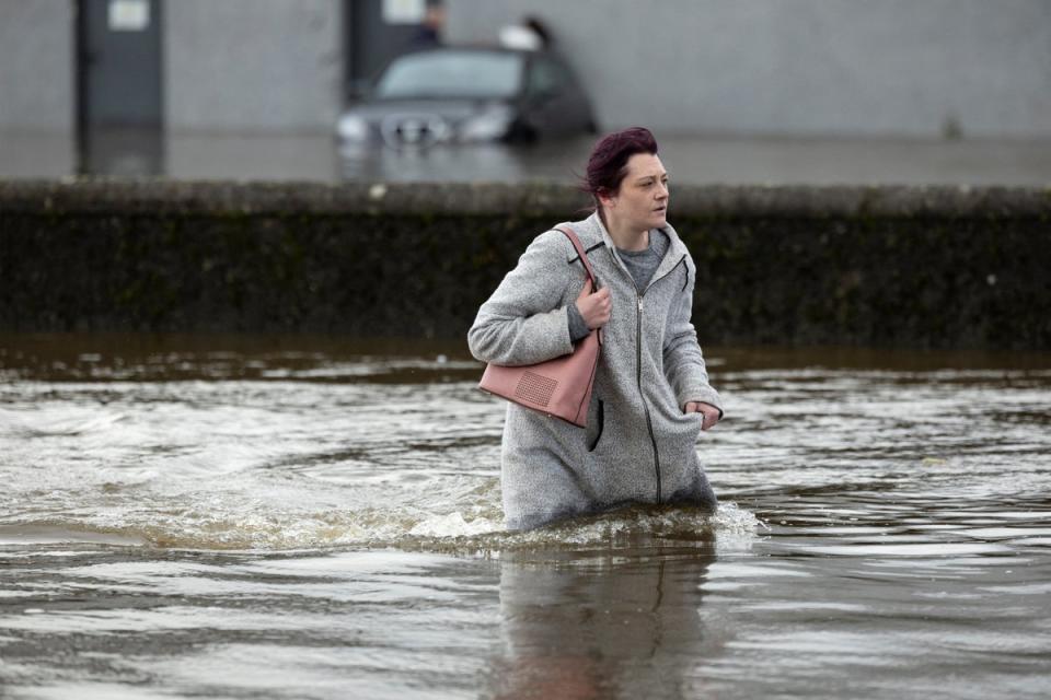 A woman tries to walk through water as it flows through the streets after heavy rain caused extensive flooding in Ireland (Reuters)