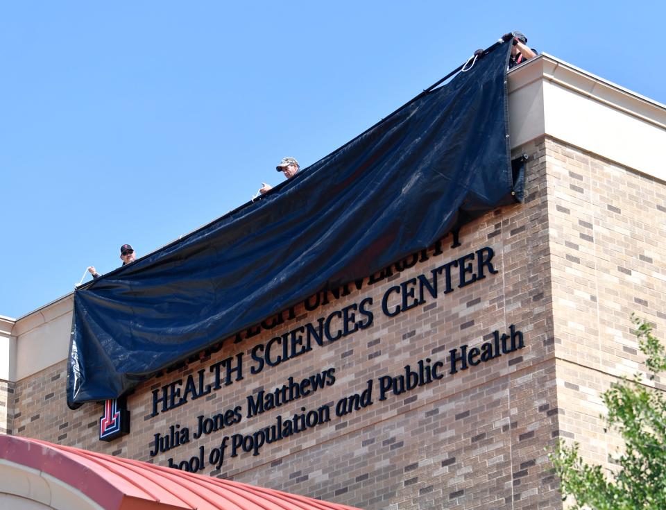 Workmen reveal the name of the Julia Jones Matthews School of Population and Public Health on Wednesday.