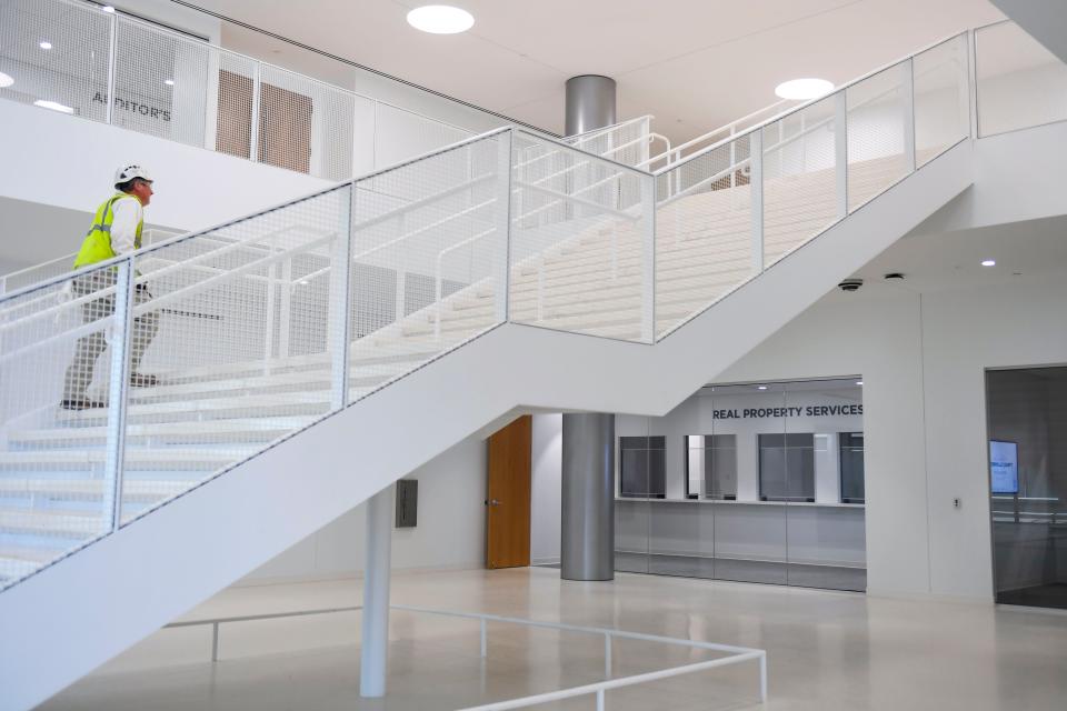 A construction crew member walks up the stairs in the lobby of the new Greenville County government building on the corner of Church Street and University Ridge on Thursday, March 9, 2023.