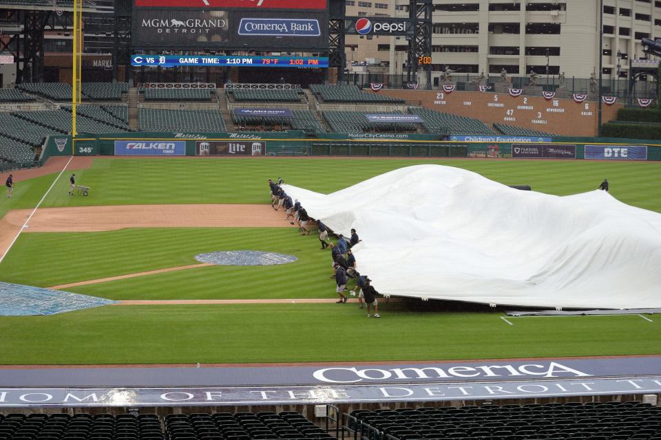 The Tigers' ground crew covers the field as rain falls before action against the Cincinnati Reds at Comerica Park, Saturday, August 1, 2020.