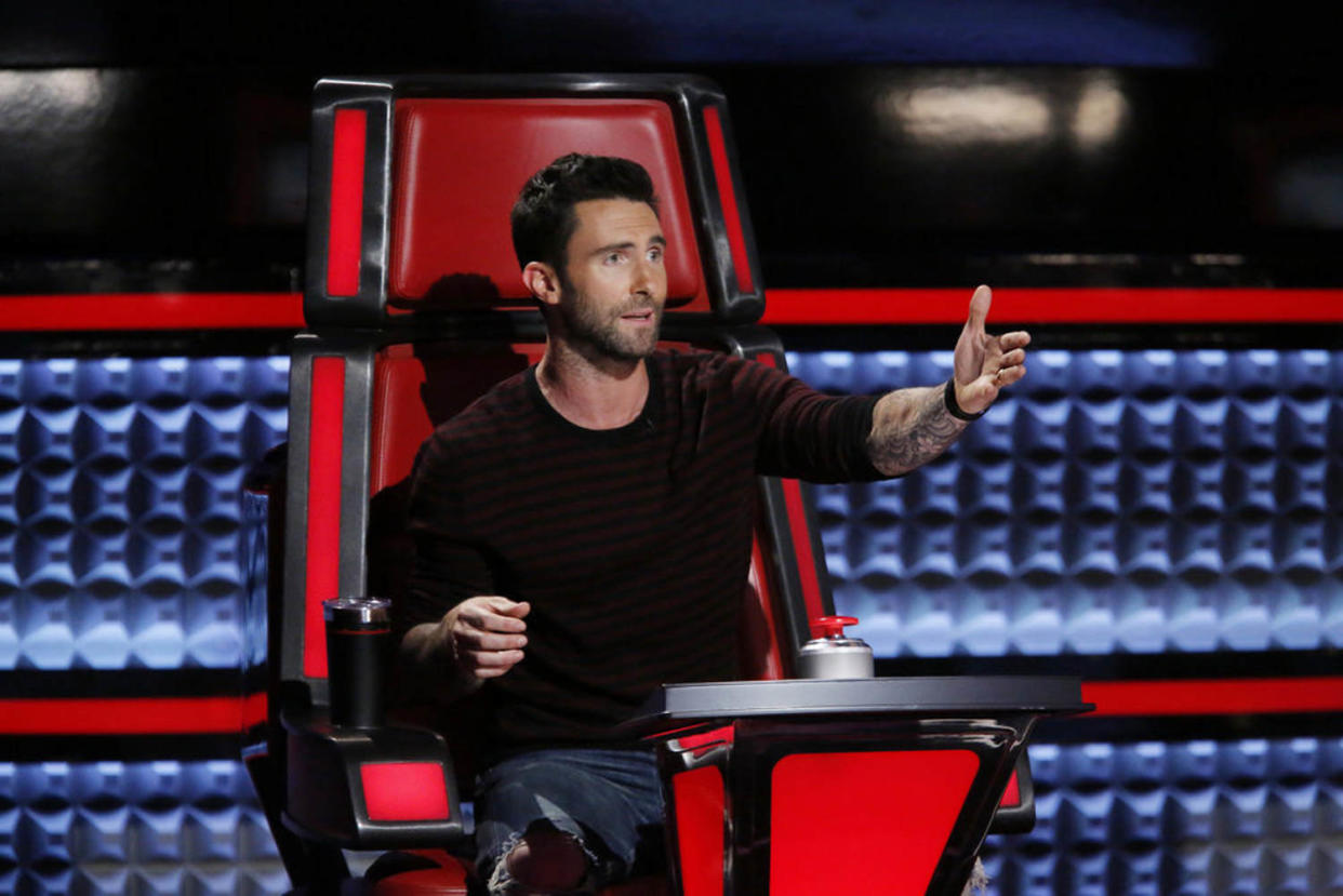 Adam Levine in a red chair on the set of 