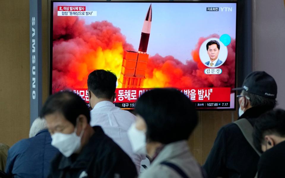 People walk past a news broadcast in Seoul railway station of a missile launch - Ahn Young-joon/AP