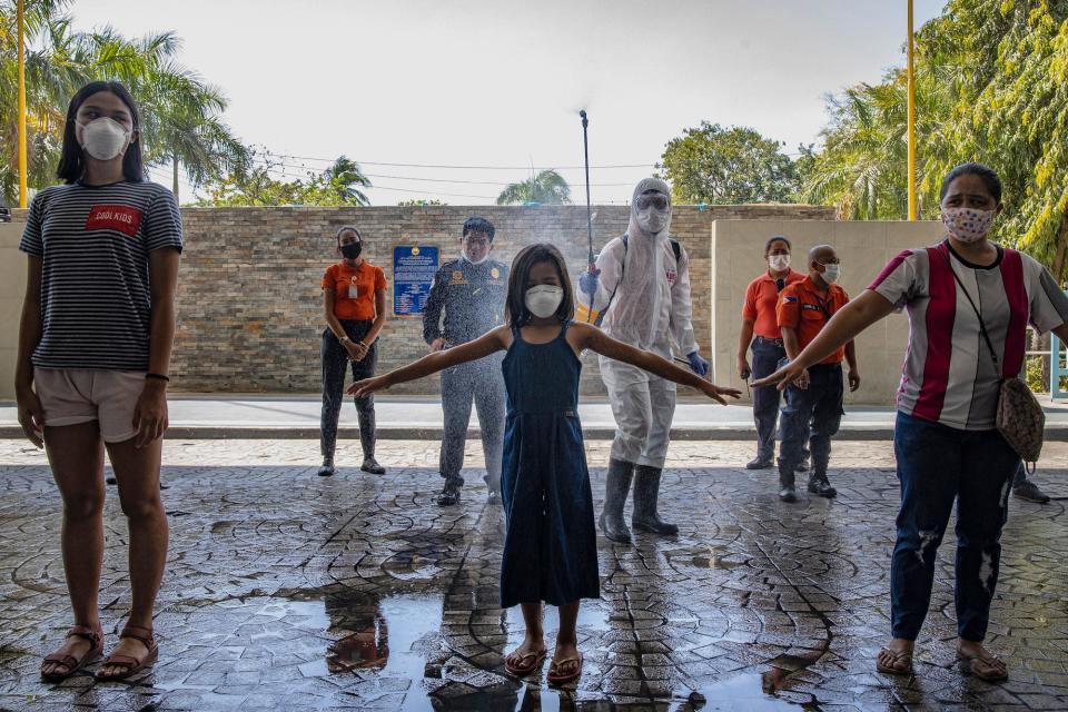 Visitors are sprayed with disinfectant before entering a government office building to curb the spread of COVID-19 on March 19, 2020 in Pasig city, Metro Manila, Philippines.