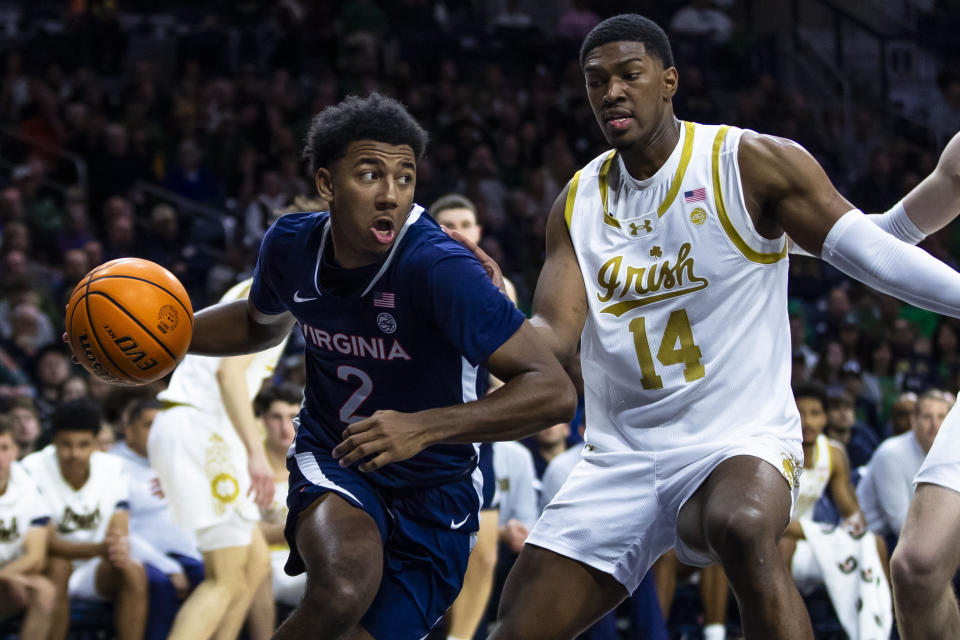 Virginia's Reece Beekman (2) drives as Notre Dame's Kebba Njie (14) defends him during the first half of an NCAA college basketball game on Saturday, Dec. 30, 2023, in South Bend, Ind. (AP Photo/Michael Caterina)