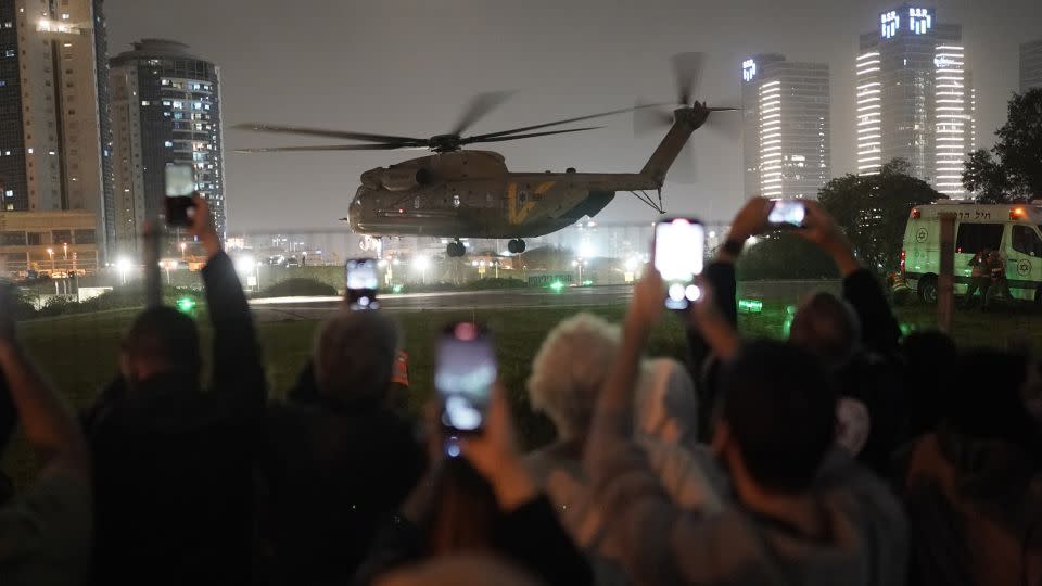 A group of Israelis watch as a helicopter carrying hostages released by Hamas lands in Petah Tikva, in Israel, on November 26. - Leo Correa/AP