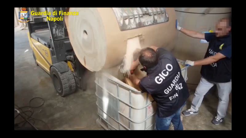 An undated handout image shows Italian finance police officers opening a paper cylinder that contains ISIS produced amphetamine pills in Salerno