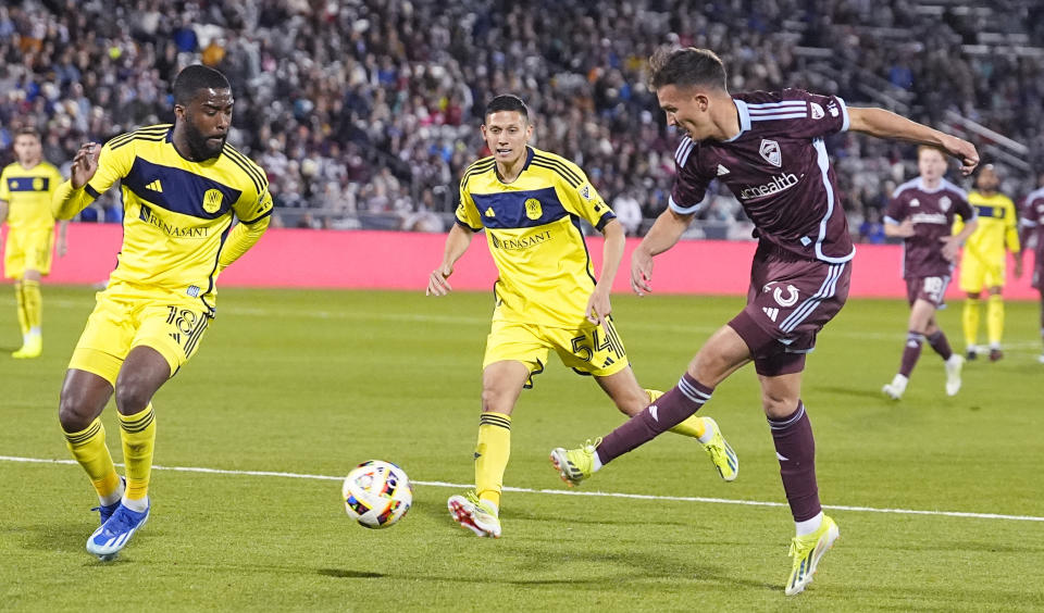 Colorado Rapids midfielder Cole Bassett, right, kicks the ball as Nashville SC defender Shaq Moore, left, and midfielder Sean Davis, center, cover during the first half of an MLS soccer match Saturday, March 2, 2024, in Commerce City, Colo. (AP Photo/David Zalubowski)