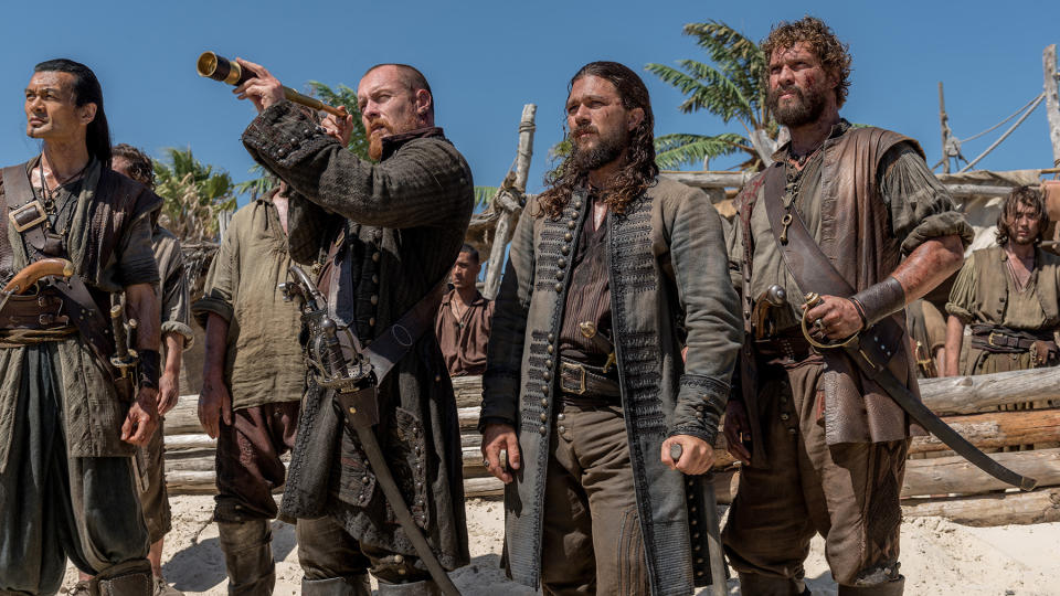 Winston Chong, Toby Stephens, Luke Arnold and Laudio Liebenberg in costume as pirates on a beach in 