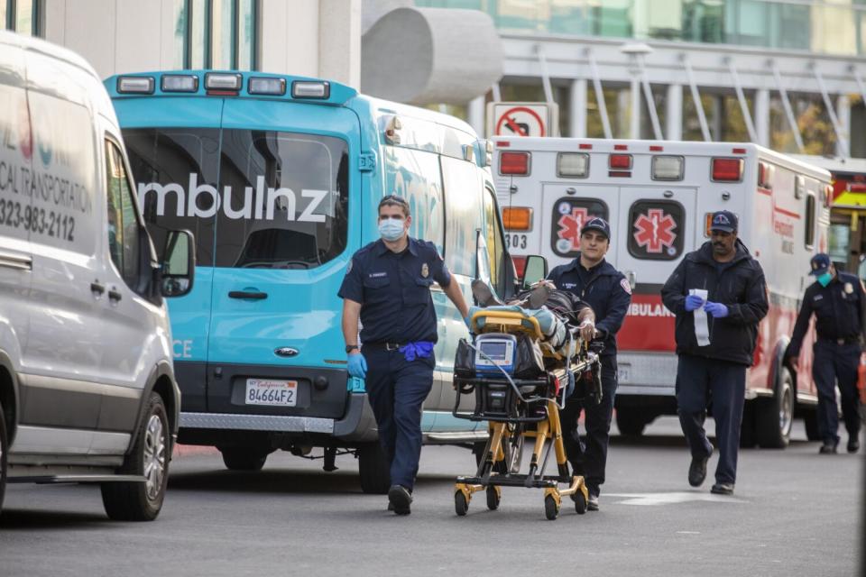 EMTs pushing a stretcher beside parked ambulances