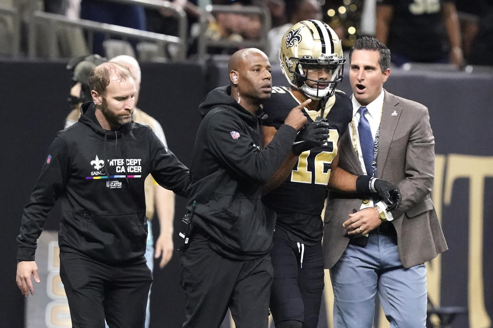 New Orleans Saints wide receiver Chris Olave is escorted off the field by medical personnel after catching a touchdown pass from quarterback Andy Dalton during an NFL football game in New Orleans, Sunday, Oct. 9, 2022. (AP Photo/Gerald Herbert)