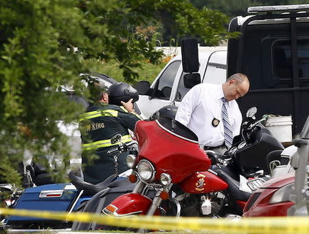 A police officer inspects a motorcycle before it is towed away from the Twin Peaks restaurant, where nine members of a motorcycle gang were shot and killed, in Waco, May 19, 2015. REUTERS/Mike Stone