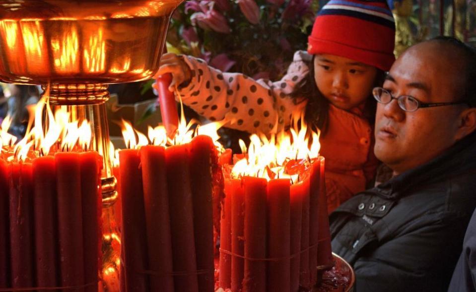 A young girl lights a prayer candle at Taipei’s Longshan Temple.