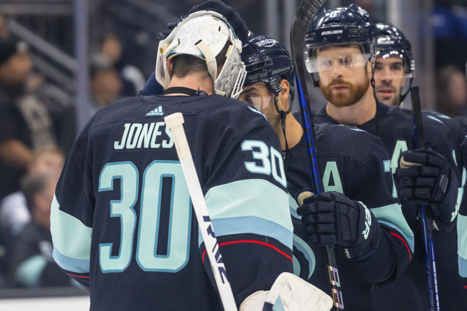 Seattle Kraken players including goalie Martin Jones, left, forward Jordan Eberle, second from left, and defenseman Adam Larsson, second from right, celebrate after an NHL hockey game, Sunday, Jan. 1, 2023, in Seattle. The Kraken won 4-1. (AP Photo/Stephen Brashear)