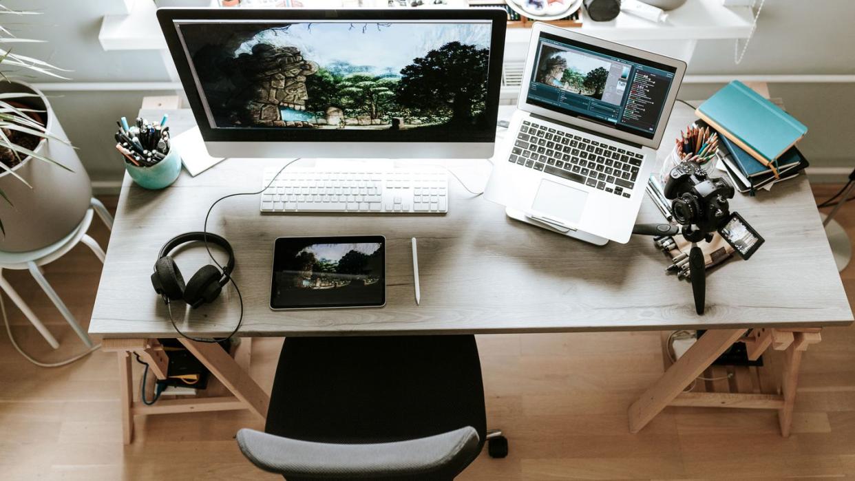 work from home desk with monitor laptop headphones and digital camera