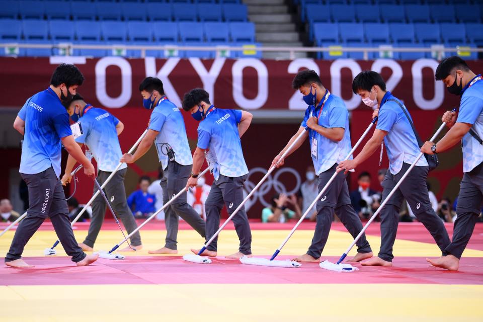 <p>Volunteers clean and disinfect mats during the judo competition during the Tokyo 2020 Olympic Games at the Nippon Budokan in Tokyo on July 24, 2021. (Photo by Franck FIFE / AFP)</p> 