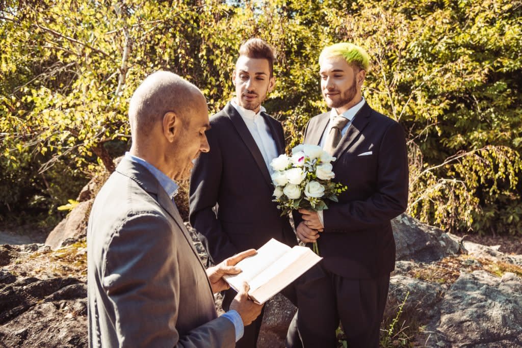 A wedding officiant weds two grooms. 
