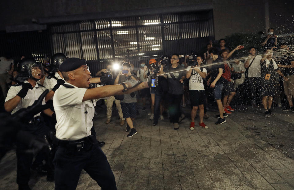 Police officers use pepper spray against protesters in a rally against the proposed amendments to the extradition law at the Legislative Council in Hong Kong during the early hours of Monday, June 10, 2019. The extradition law has aroused concerns that this legislation would undermine the city's independent judicial system as it allows Hong Kong to hand over fugitives to the jurisdictions that the city doesn't currently have an extradition agreement with, including mainland China, where a fair trial might not be guaranteed. (AP Photo/Vincent Yu)