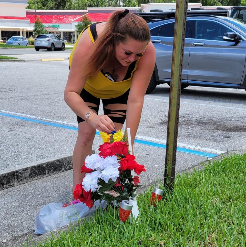 Terri Barnes places a cross, flowers and lights on July 11 at the ATM on Bowden Road where her son Jamarion Barnes, 21, and girlfriend Tyniya Powell, 20, were gunned down in late June.