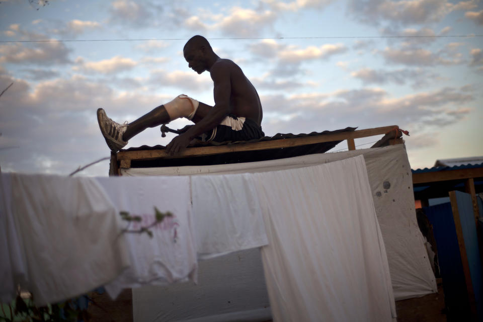 In this picture taken on Feb. 11, 2012, Gobert Loulien, 36, a former construction worker and father of four, whose left leg was amputated due to an injury suffered in the 2010 earthquake, makes repairs on the roof of his bathhouse at La Piste camp in Port-au-Prince, Haiti. While more than a million people displaced by the 2010 quake ended up in post-apocalyptic-like tent cities, some of the homeless people with disabilities landed in the near-model community of La Piste, a settlement of plywood shelters along tidy gravel lanes. However, the rare respite for the estimated 500-plus people living at the camp is coming to an end as the government moves to reclaim the land. (AP Photo/Ramon Espinosa)