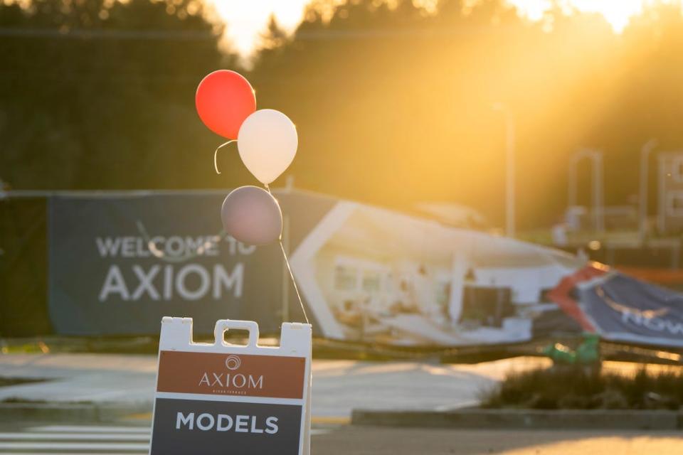 With SW Roy Rodgers road and the so-called urban growth boundary in the background, a sign for model homes is seen on Thursday, Feb. 22, 2024, in the southwest Portland, Ore., suburb of Tigard. The boundary was established by a 1973 law that placed boundaries around cities to prevent urban sprawl and preserve nature and farmland. (AP Photo/Jenny Kane)