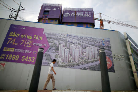 A man walks past an advertisement promoting an apartment complex which is currently under construction in Yongin, South Korea, August 24, 2016. REUTERS/Kim Hong-Ji