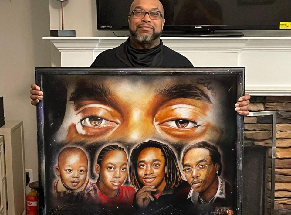 In this photo from Nov. 16, 2022, Kenneth Ball poses with a portrait of his son, Migos hip-hop group member Takeoff, drawn by Athens artist Ronnie B. "Ron Da Don" Hull.