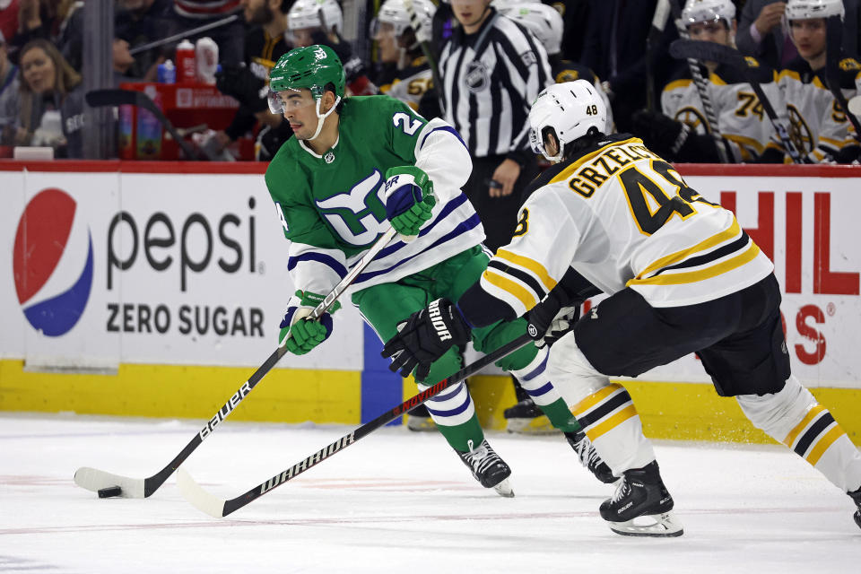 Carolina Hurricanes' Seth Jarvis (24) is challenged by Boston Bruins' Matt Grzelcyk (48) during the second period of an NHL hockey game in Raleigh, N.C., Sunday, March 26, 2023. (AP Photo/Karl B DeBlaker)