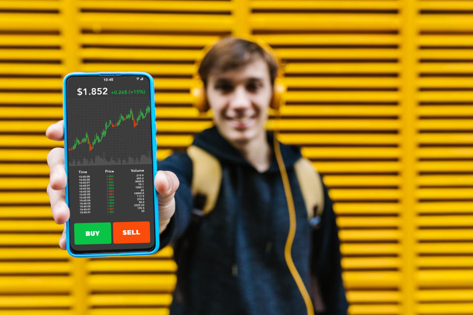 Young male investor showing smart phone screen with stock market investment app