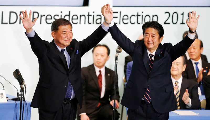 Japan's PM Abe, who is also the ruling LDP leader, raises his hands with former defence minister Ishiba after Abe won the ruling party leadership vote at the party's headquarters in Tokyo