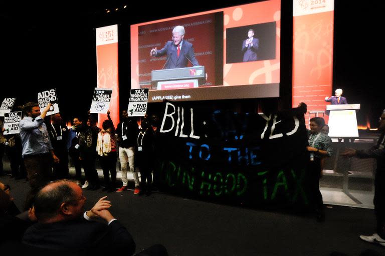 Protestors raise placards as former US president Bill Clinton speaks at the International AIDS Conference in Melbourne on July 23, 2014