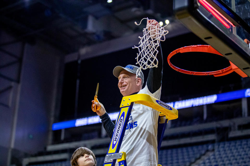 Christopher Newport coach John Krikorian holds up the net after his team captured the NCAA Division 3 men's basketball title.