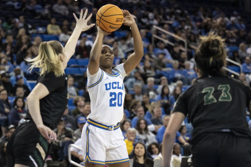 UCLA guard Charisma Osborne, center, shoots next to Sacramento State guard Benthe Versteeg.