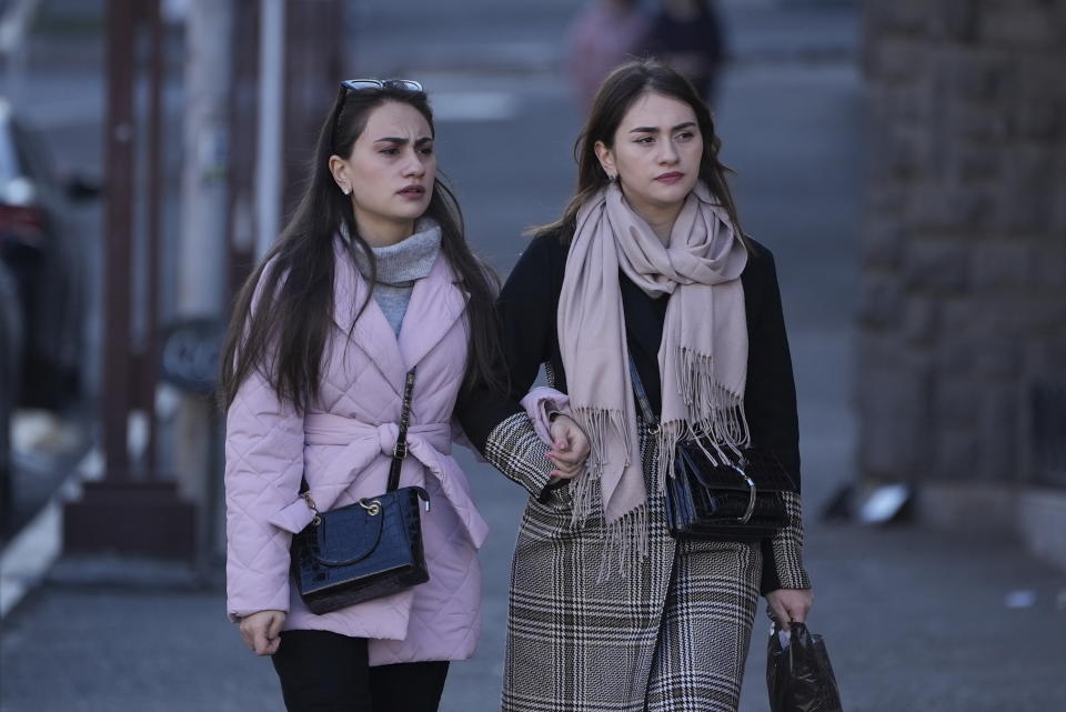 Two young women walk down in a street in Stepanakert, the capital of the separatist region of Nagorno-Karabakh, also known as Artsakh, on Sunday, Dec. 18, 2022. Protesters claiming to be ecological activists have blocked the only road leading from Armenia to Nagorno-Karabakh for more than a month, leading to increasing food shortages. Local authorities have called for a humanitarian airlift for critical supplies, but Azerbaijan has not authorized the region's airport to operate. (Edgar Harutyunyan/PAN Photo via AP)